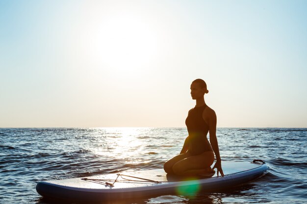 Silhouette of a Beautiful Woman Practicing Yoga on a Surfboard at Sunrise 176420 2034